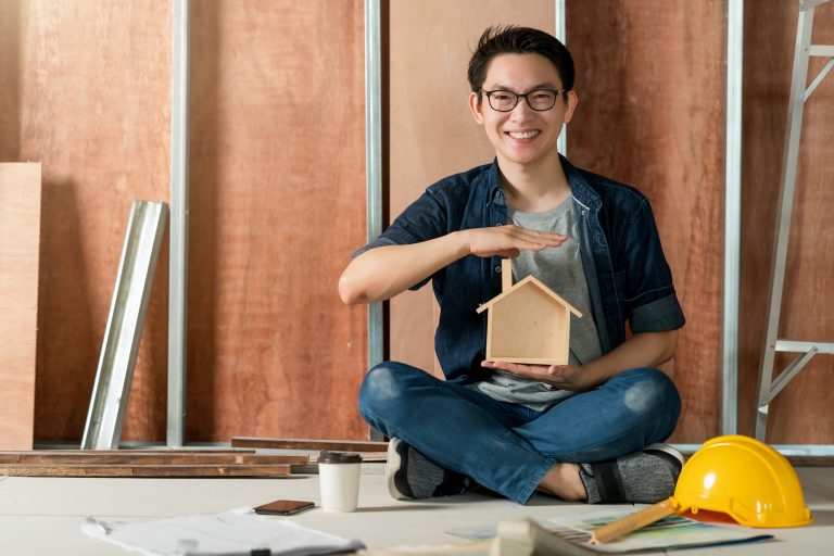 asian-attractive-glasses-interior-designer-working-house-site-renovation-construction-progress-with-smile-confident-desk-with-blue-print-drawing-tool - Sincere Moneylender